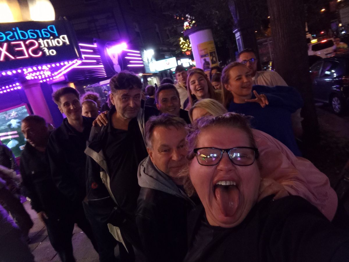 Susa mit einer lachenden Gruppe im Neonlicht auf St. Pauli