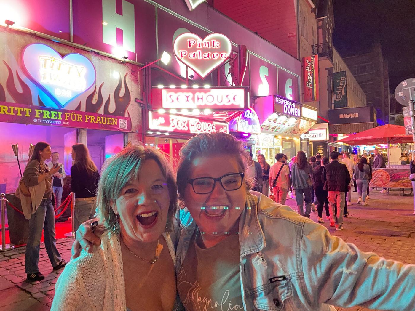 Zwei lachende Personen vor den Neonlichtern der Reeperbahn